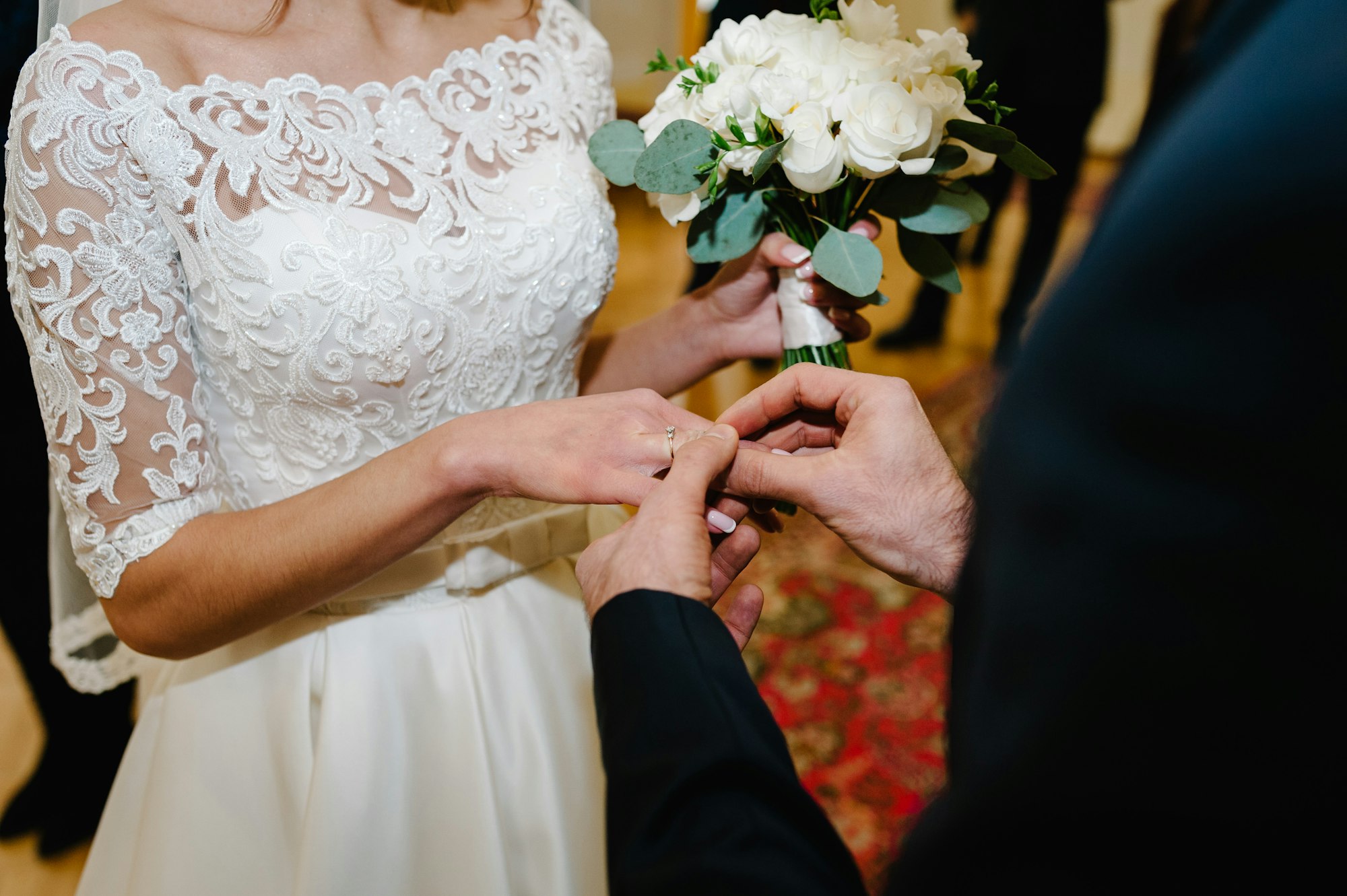 The groom's hand wears an engagement gold ring on the bride's finger. Wedding day. Hands with weddin